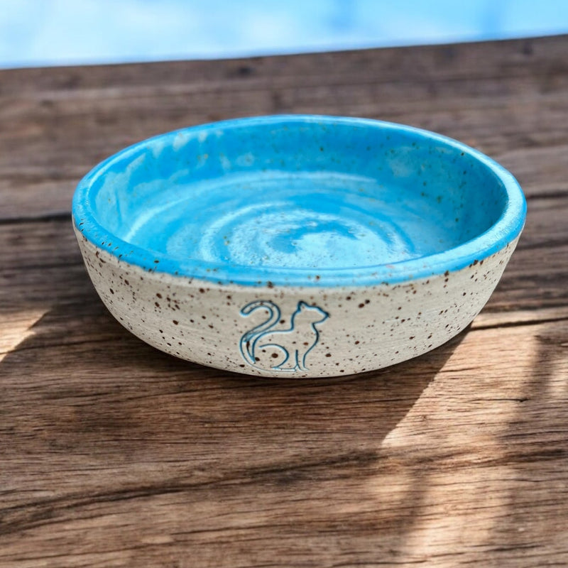 Ceramic pet food bowl with a blue interior and cat design, perfect for stylish pet feeding.