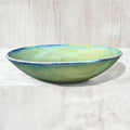 Handmade ceramic bowl in green and blue glaze, evoking nature with its unique design and vibrant colors.