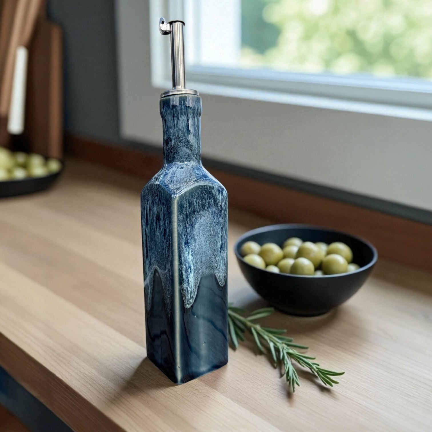 Handmade Ceramic Olive Oil Bottle with deep blue glaze and stainless steel pourer on a kitchen countertop